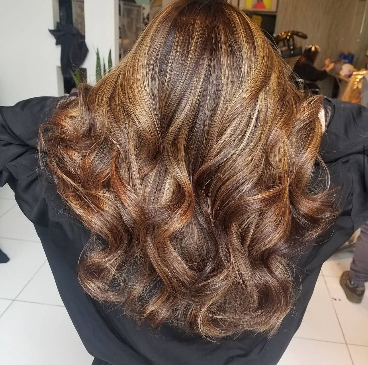 A woman with long brown hair is standing with her arms outstretched