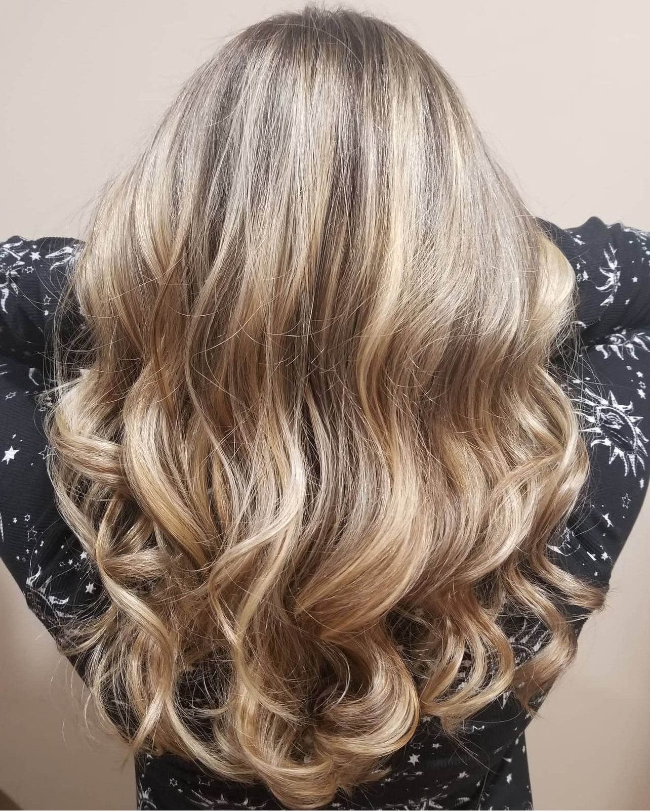 A woman with long blonde hair is wearing a black shirt with stars on it.