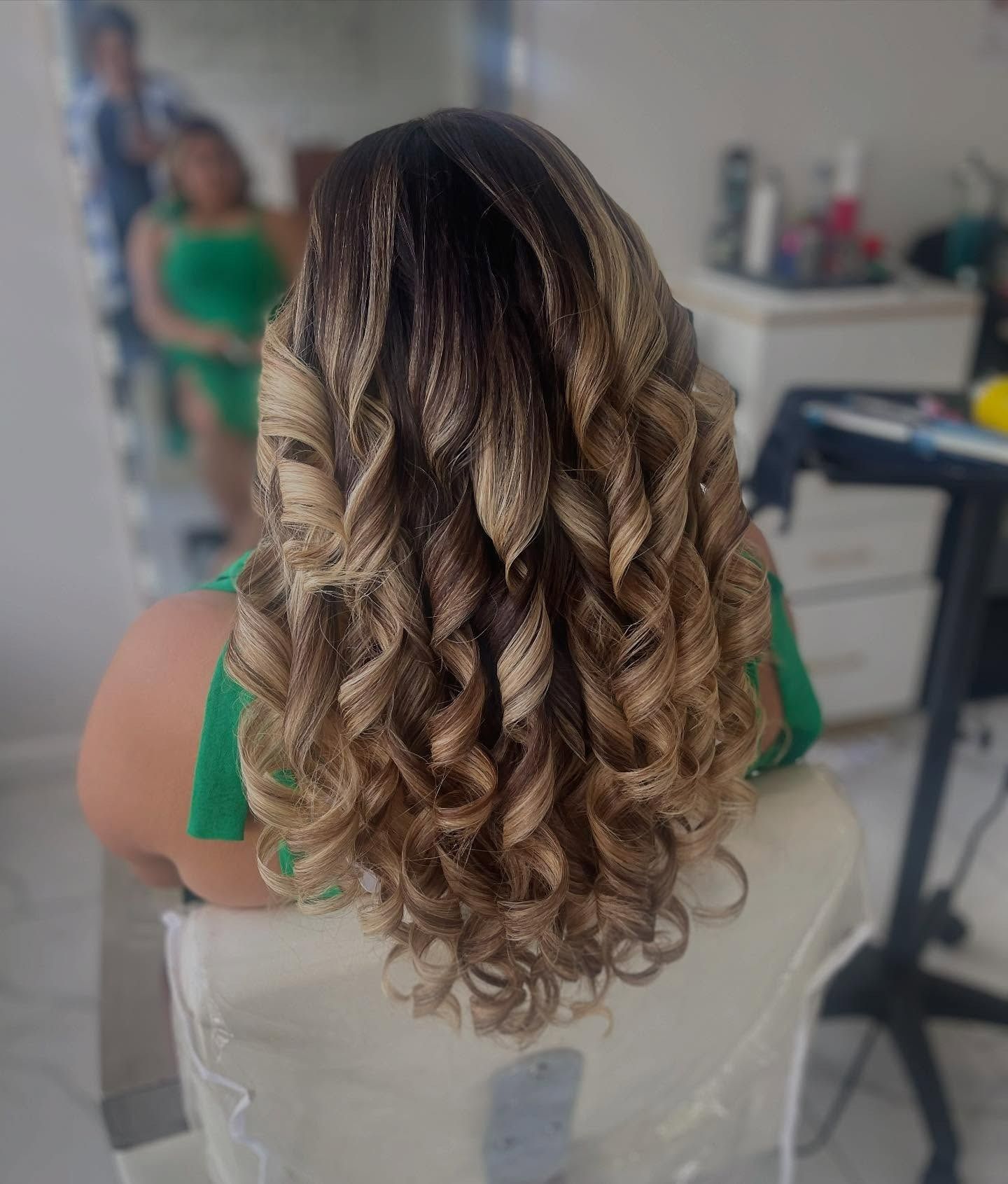 A woman with long curly hair is sitting in a chair.