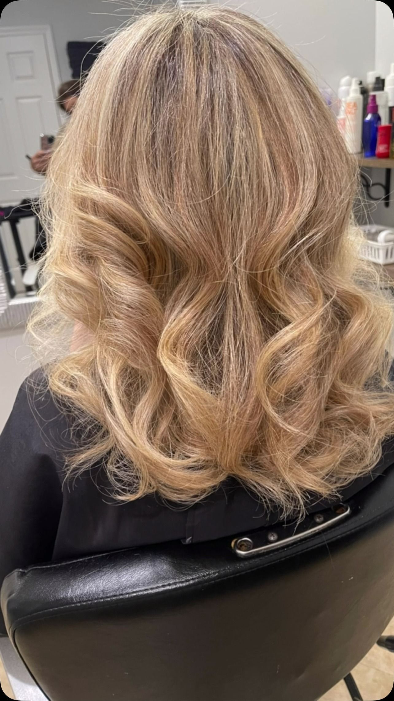 A woman is sitting in a chair with her hair in a salon.