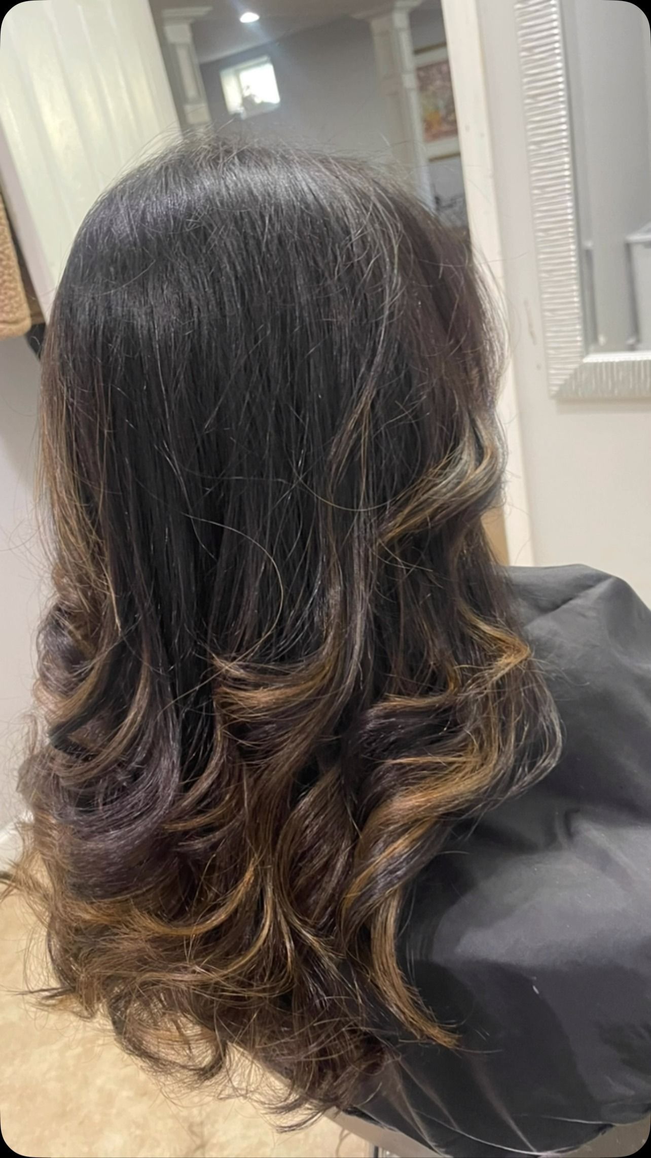 A woman is sitting in a chair with her hair in a salon.