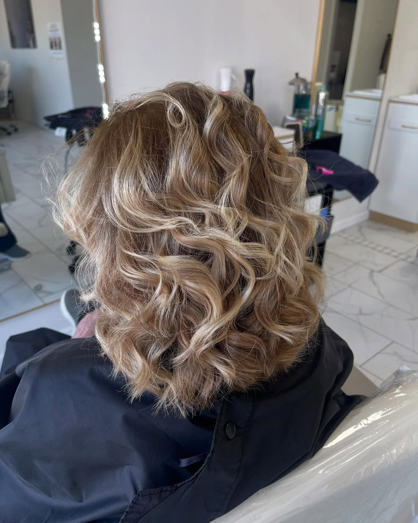 A woman is sitting in a chair with her hair in a salon.