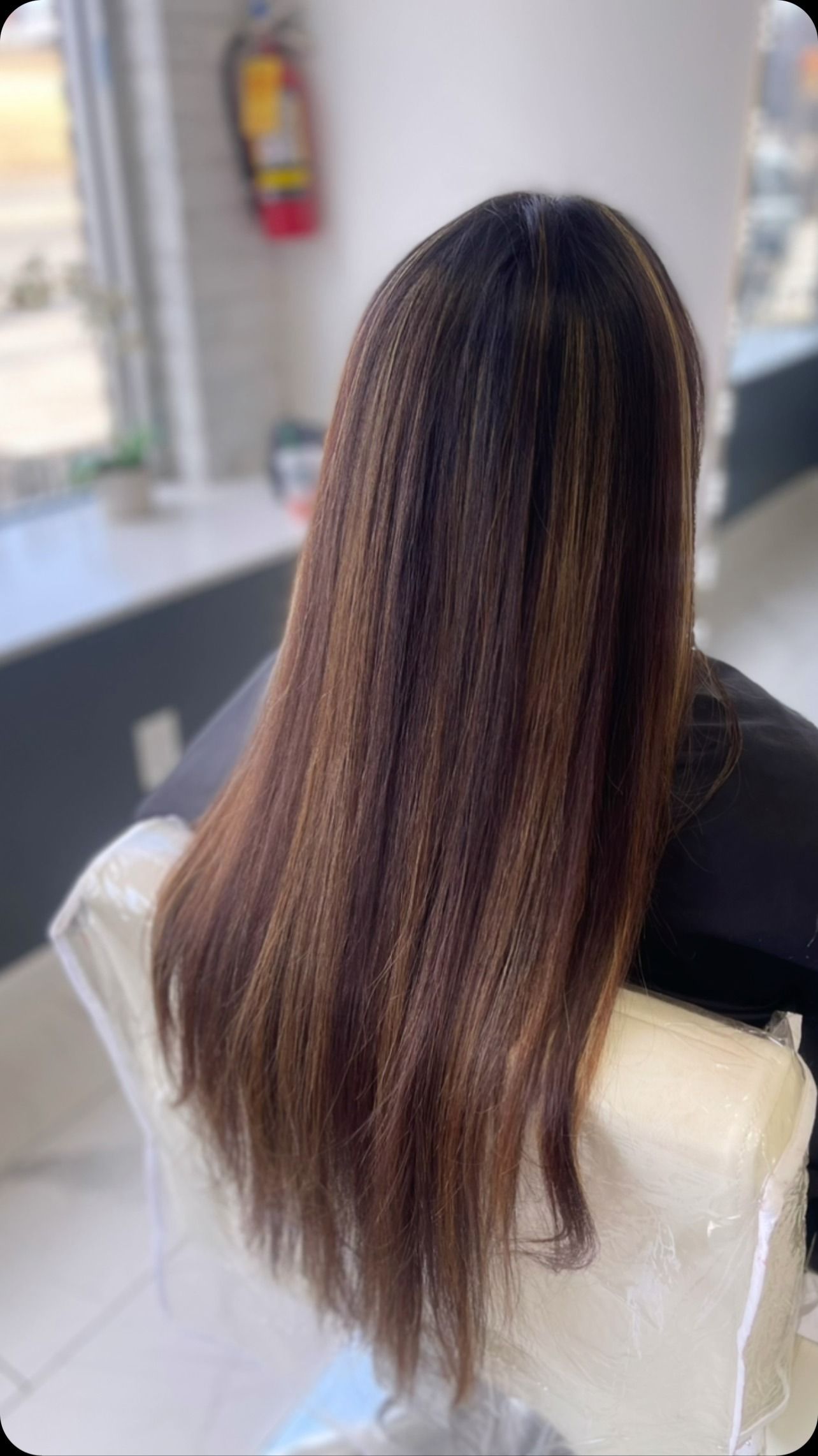 A woman with long hair is sitting in a chair in a salon.
