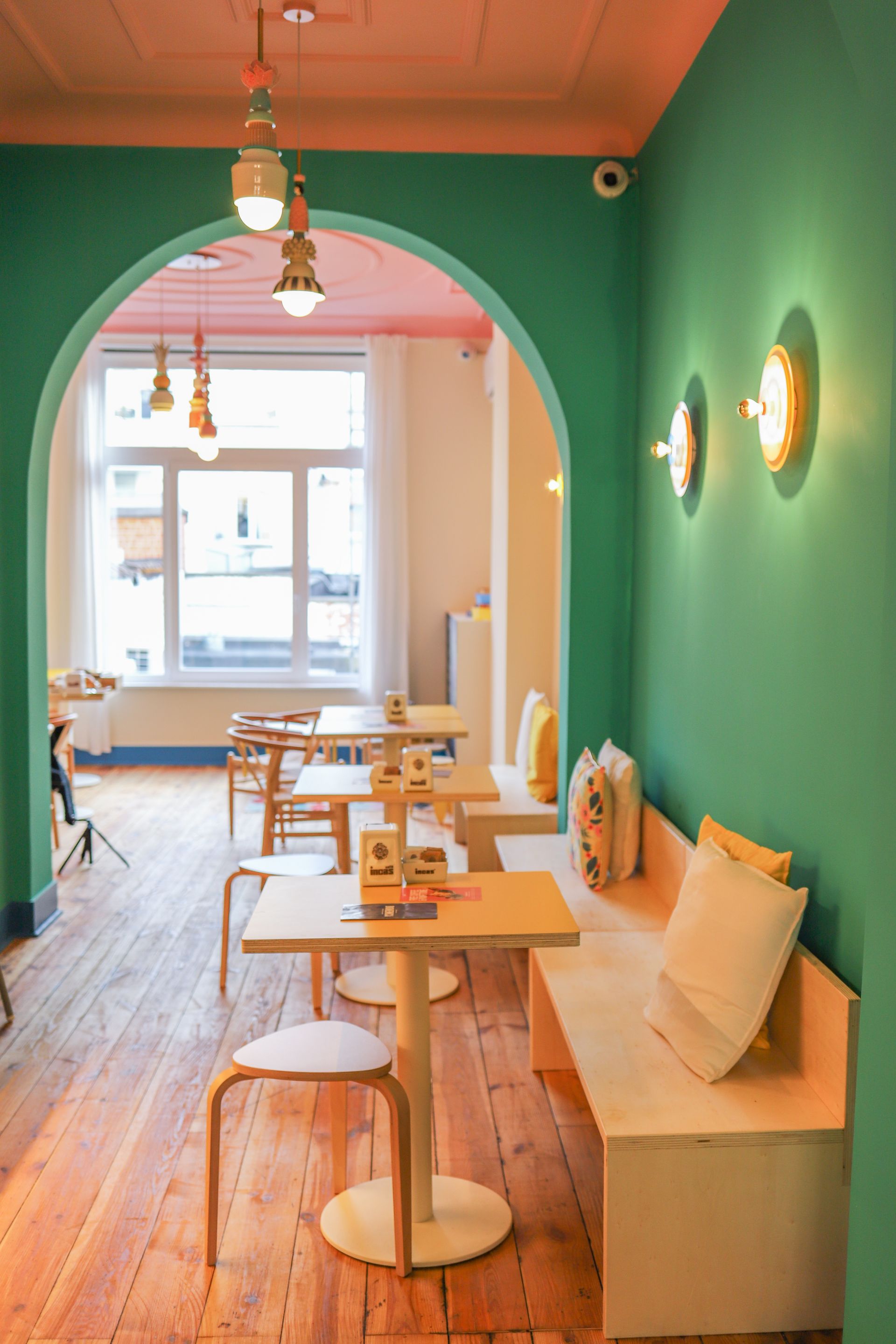 Exterior of Domenica restaurant with red chairs and awnings, a white facade, and large windows.