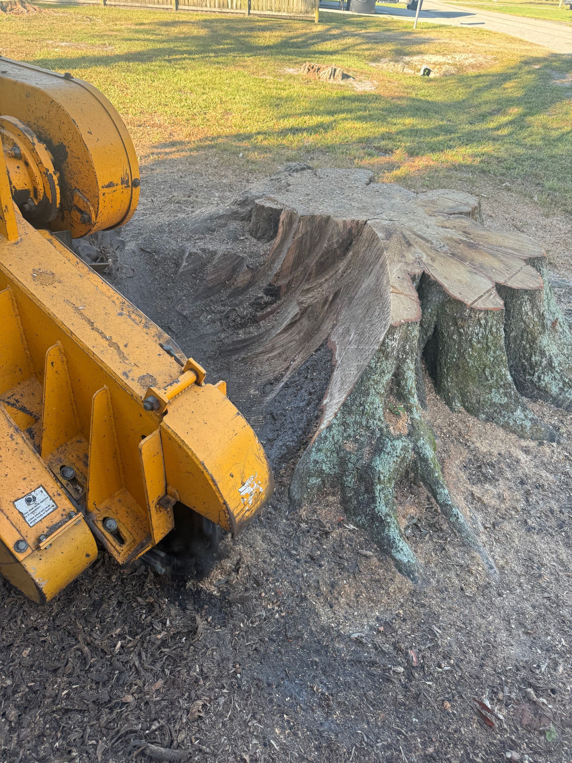 Yellow excavator bucket lifting dark gravel into a small pile on a grassy outdoor site