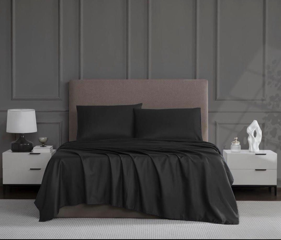 Sábanas grises en una cama con cabecero gris. Mesillas de noche a ambos lados con lámparas y adornos.