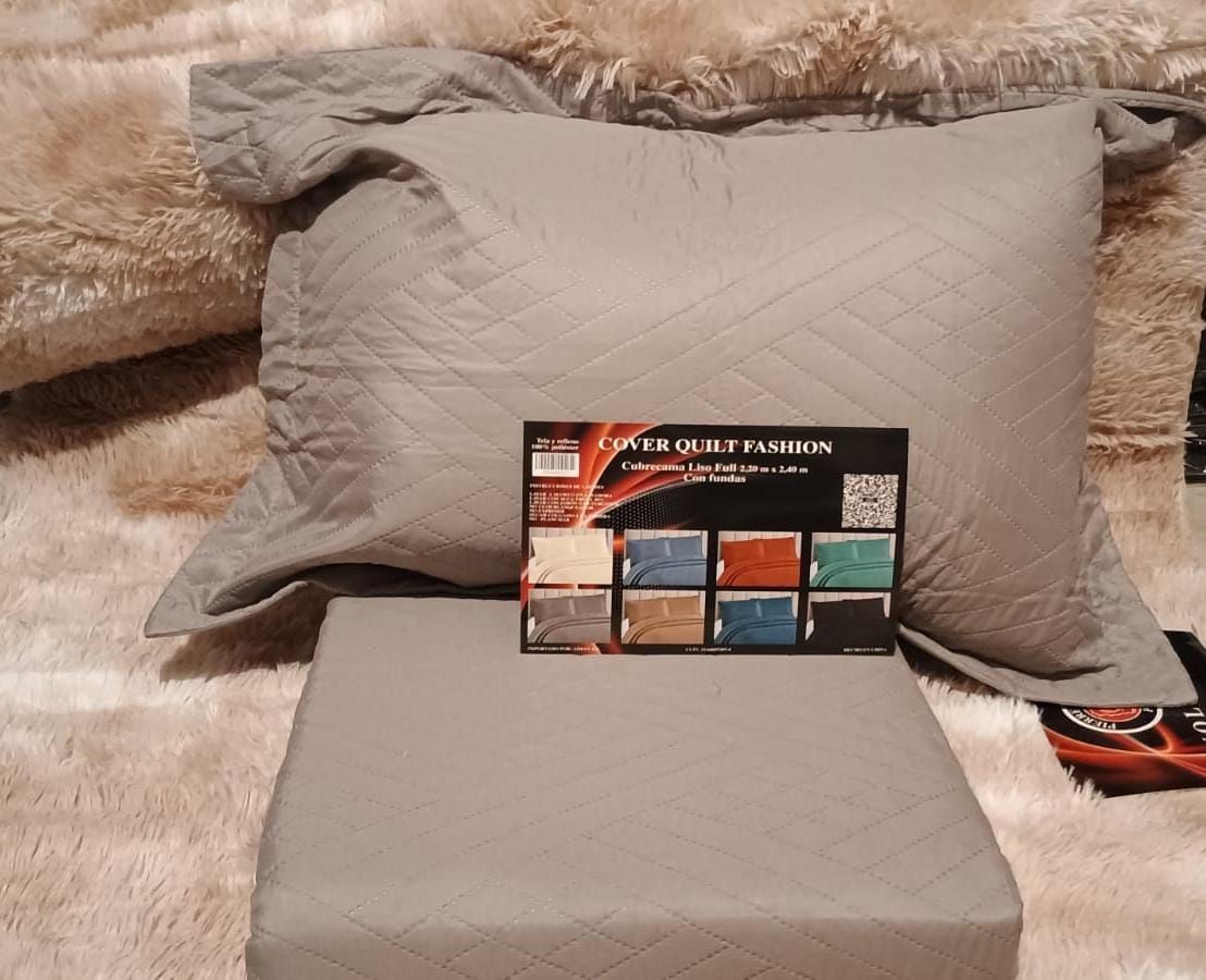 Almohada y cojín acolchados de color gris sobre una alfombra peluda con una tarjeta de muestra de color en el frente.