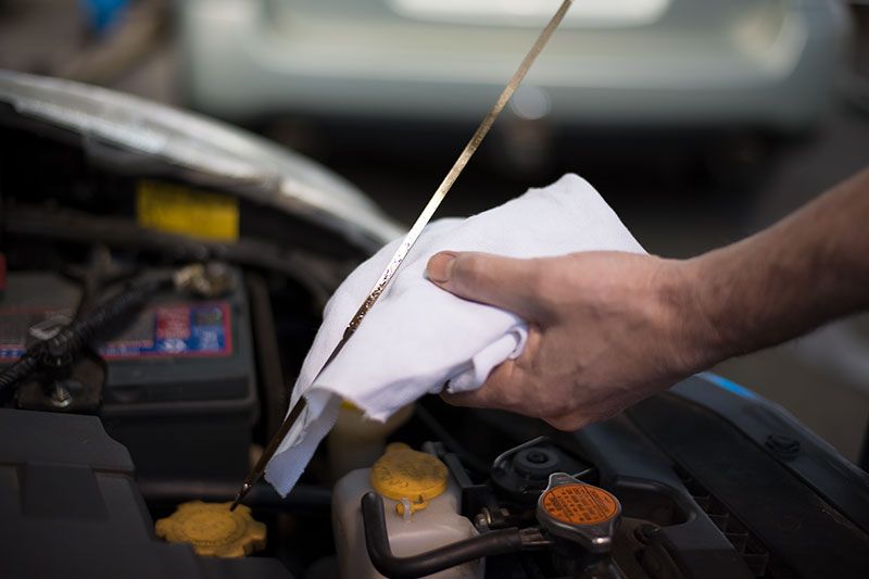 A Person Is Checking the Oil Level of A Car with A Dipstick — Marsh Mechanics and Auto Electrical in Maddingley, VIC