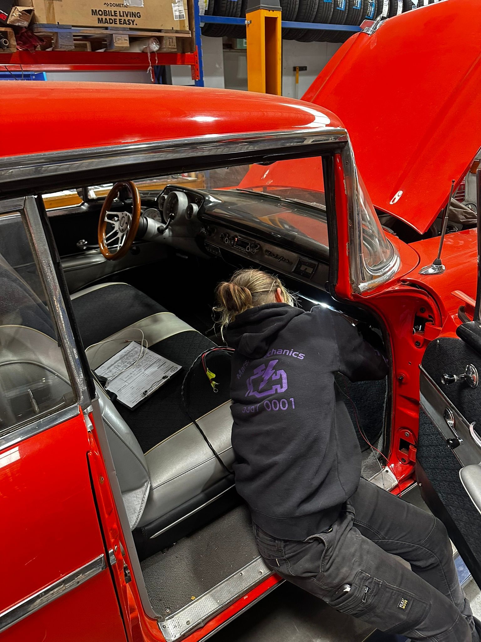 A Woman Bending Down Working On A Red Car — Marsh Mechanics and Auto Electrical in Maddingley, VIC