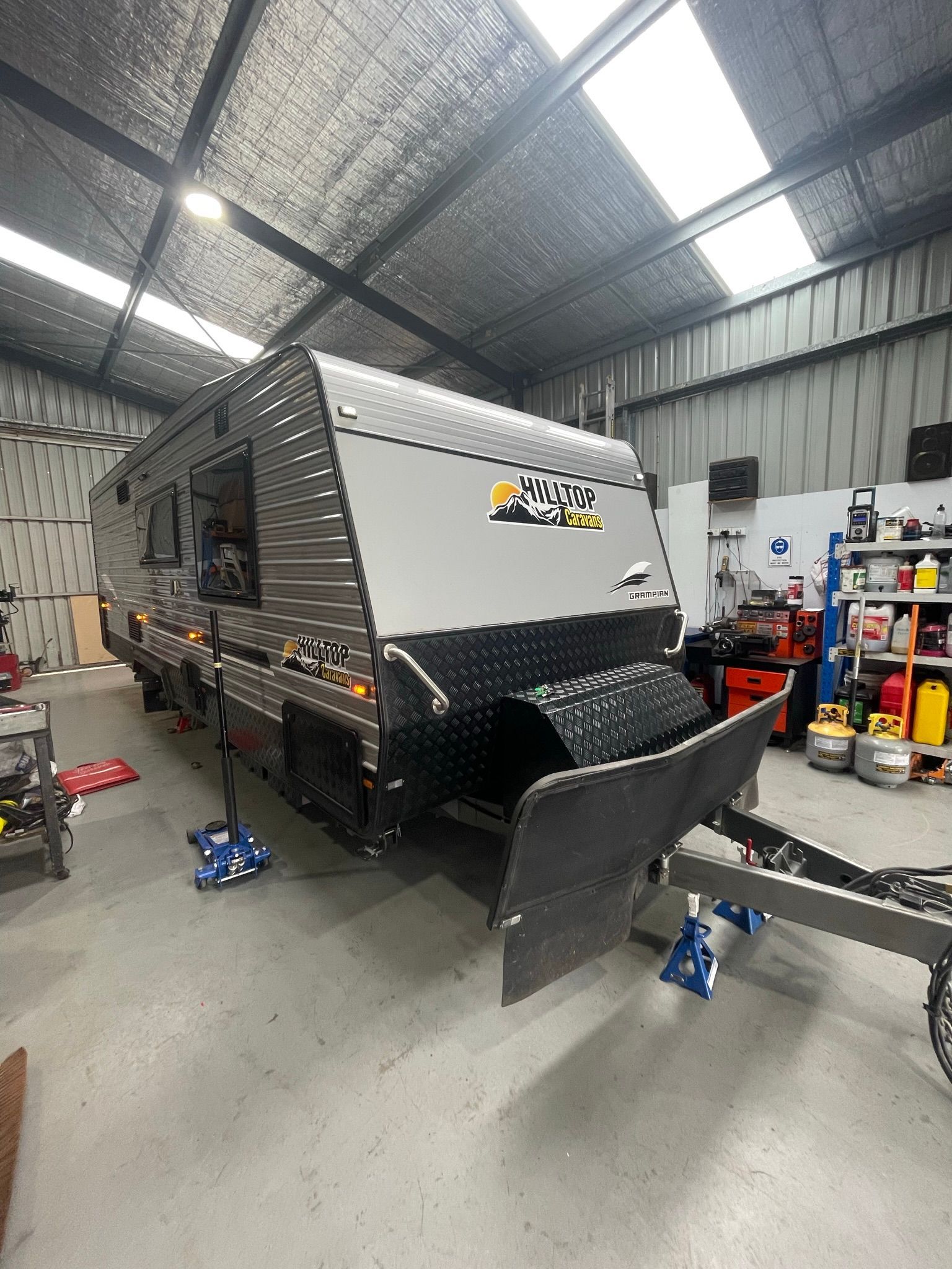 A Caravan Lifted on A Hydraulic jacks in A Garage — Marsh Mechanics and Auto Electrical in Maddingley, VIC