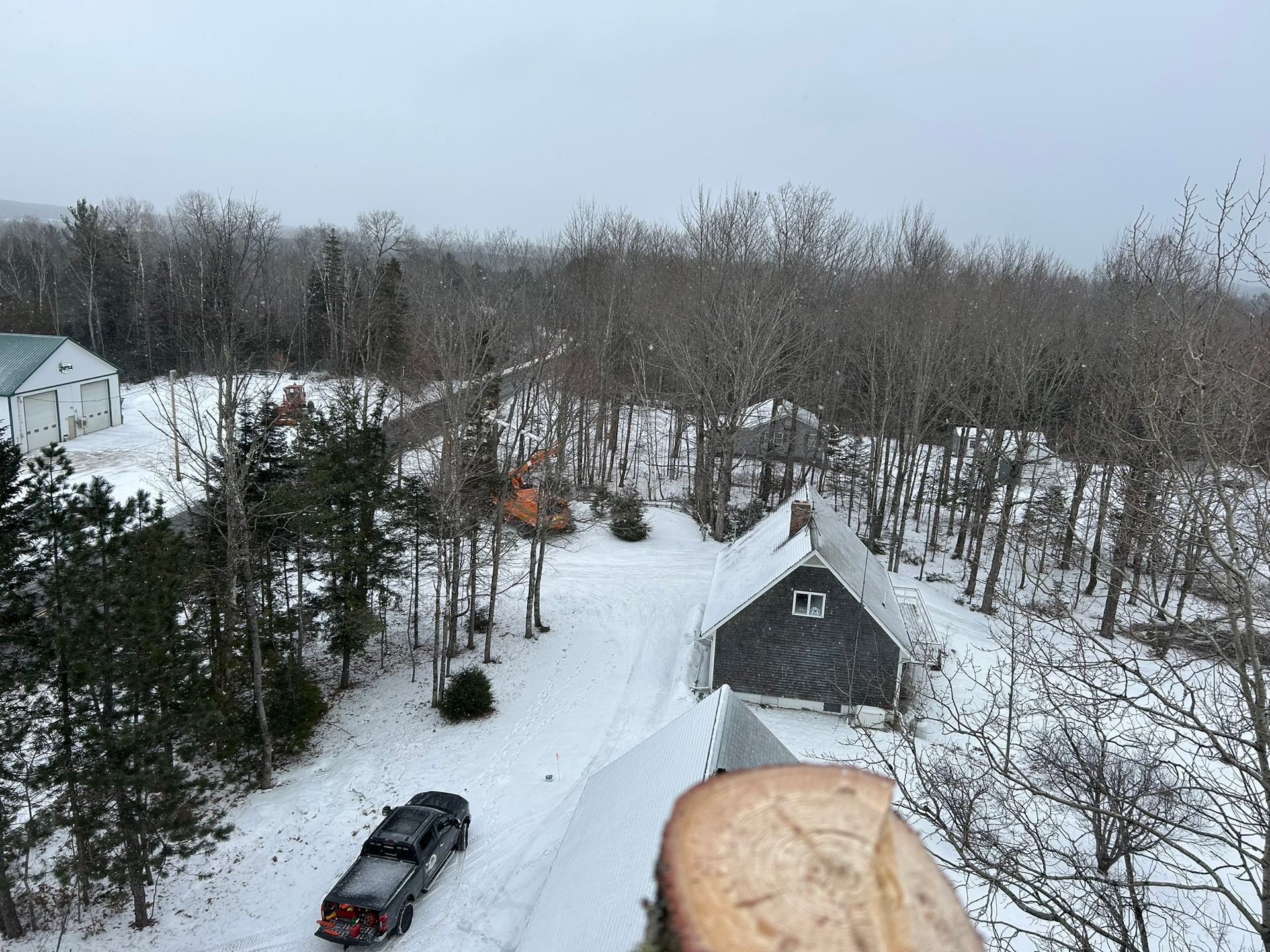 An aerial view of a snowy landscape with a truck parked on the side of the road.