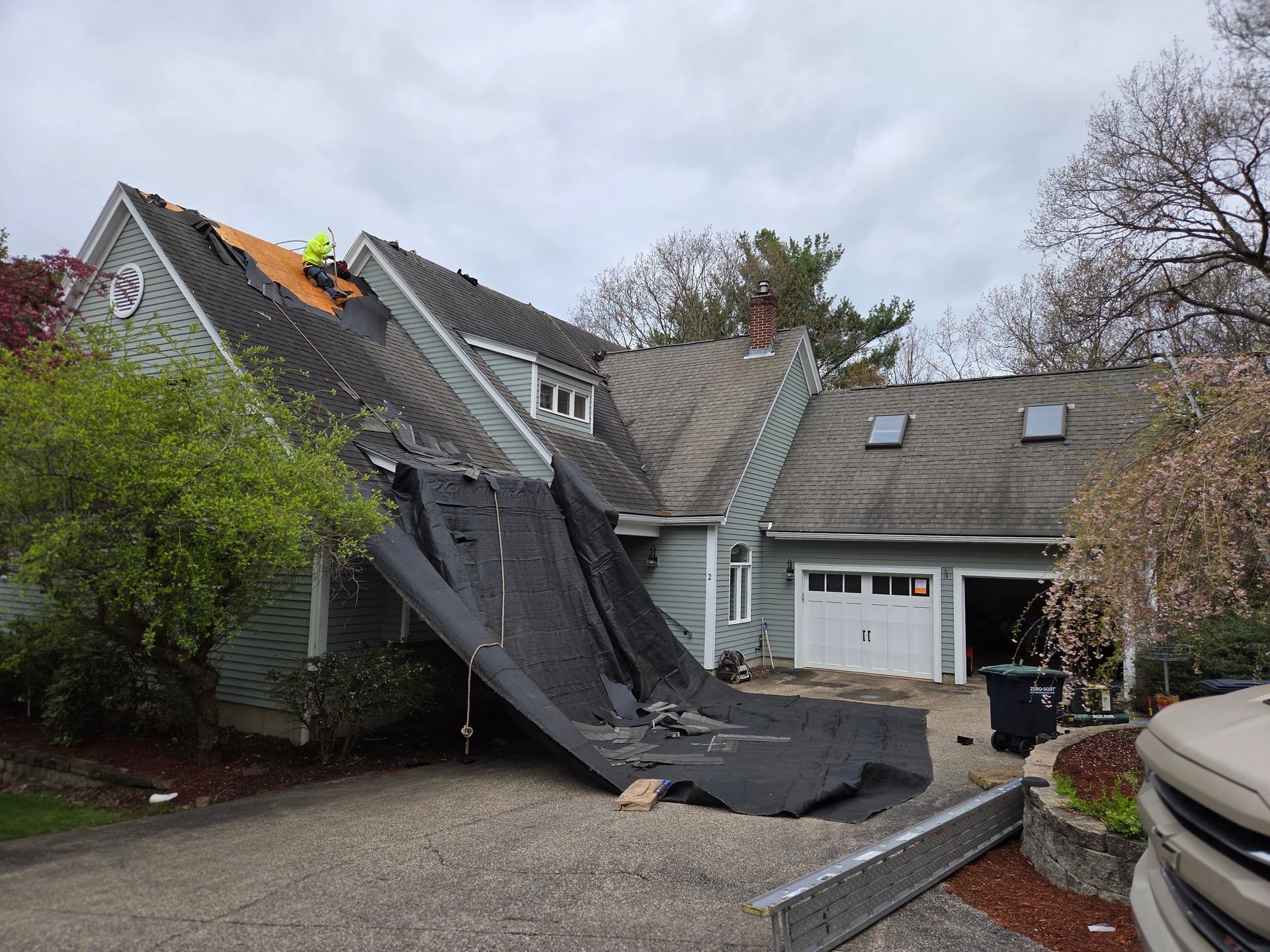 Collapsed roof under repair on a suburban house, with black tarp draped over the damaged section