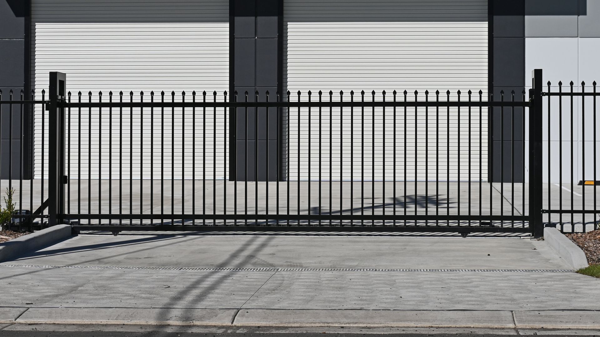 A black metal fence is sitting in front of a garage door.