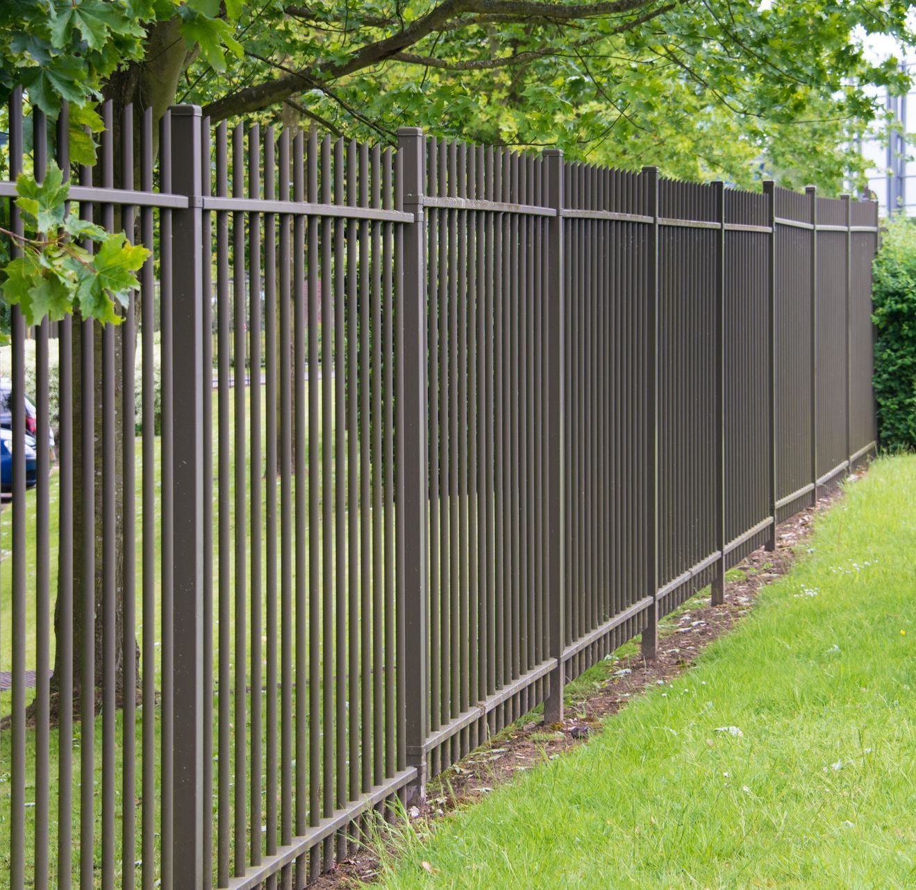 A long metal fence surrounds a lush green field.