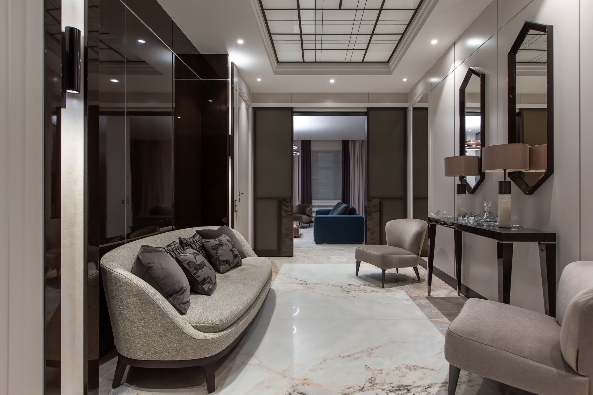 Elegant hallway with a curved sofa, marble floors, mirrors, and a glimpse of a living room.