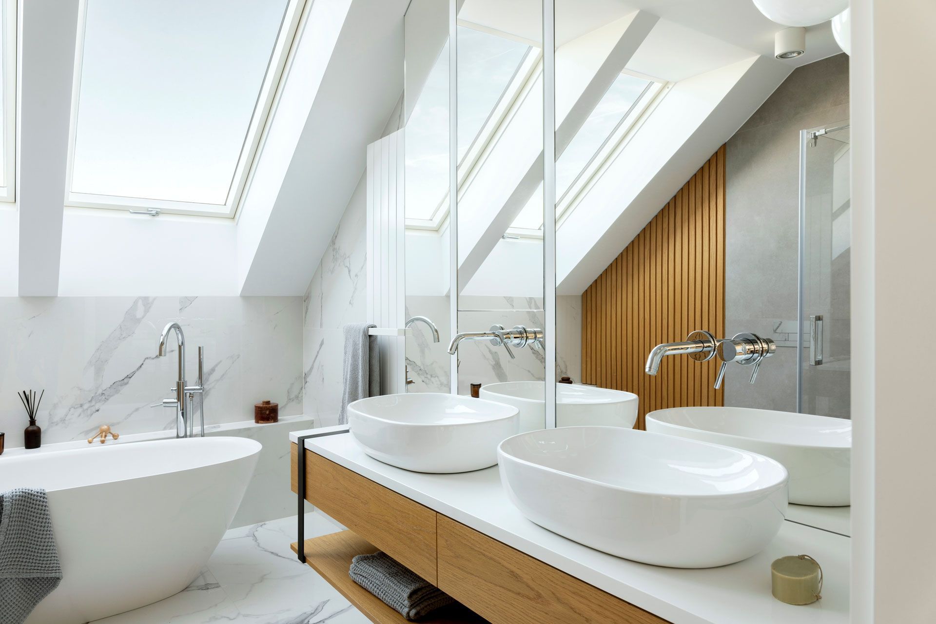 Modern bathroom with skylights, featuring a freestanding tub, double sinks, and wooden accents.