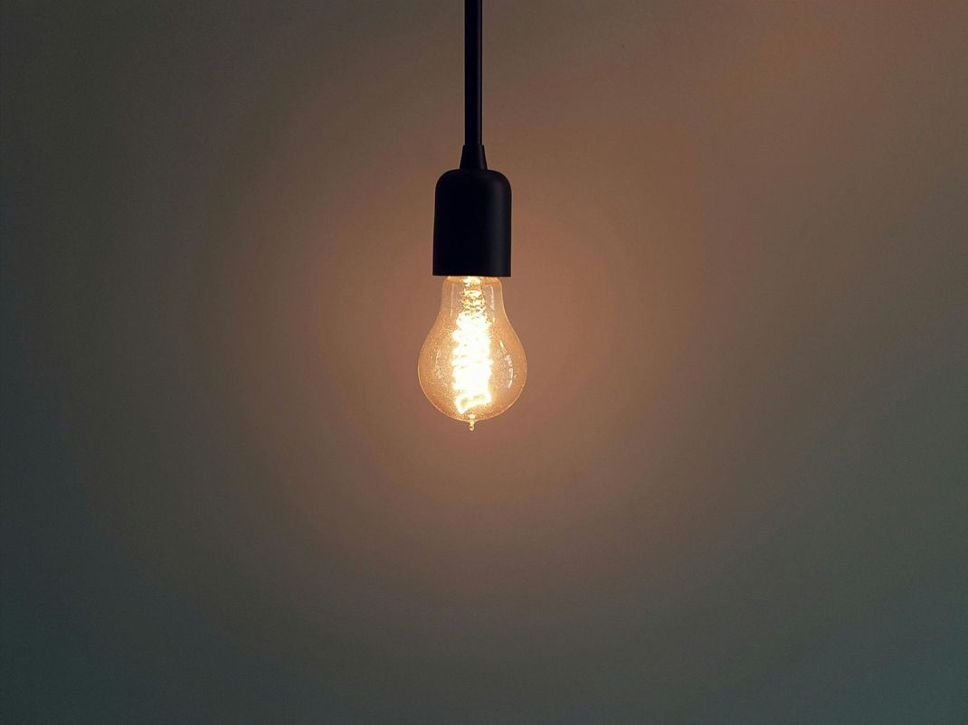A light bulb is hanging from a ceiling and is lit up.