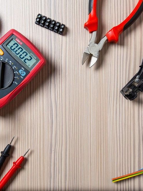A bunch of electrical tools are on a wooden table.