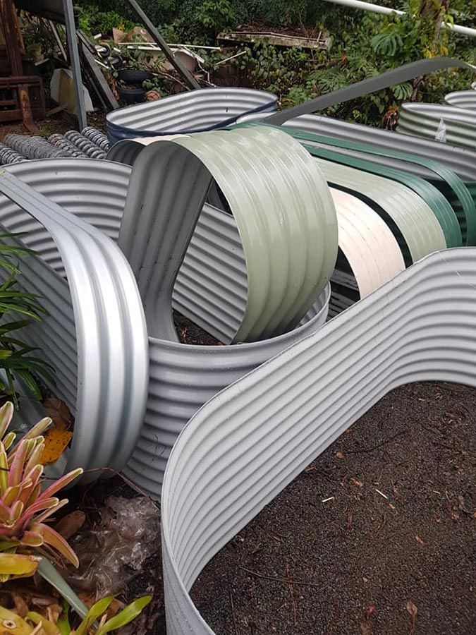 A Bunch of Corrugated Metal Tubes Are Stacked on Top of Each Other in a Garden — Foley's Tanks in Maleny, QLD