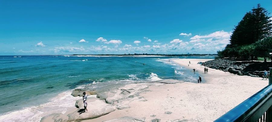 A Beach With People Walking on It and a Body of Water in the Background — Foley's Tanks in Caloundra, QLD