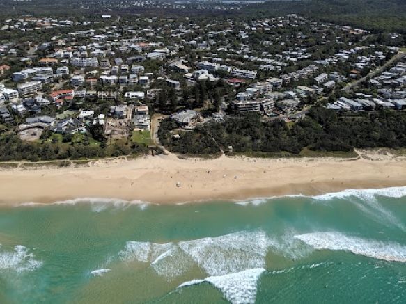An Aerial View of a Beach With Waves and a City in the Background — Foley's Tanks in Noosa, QLD
