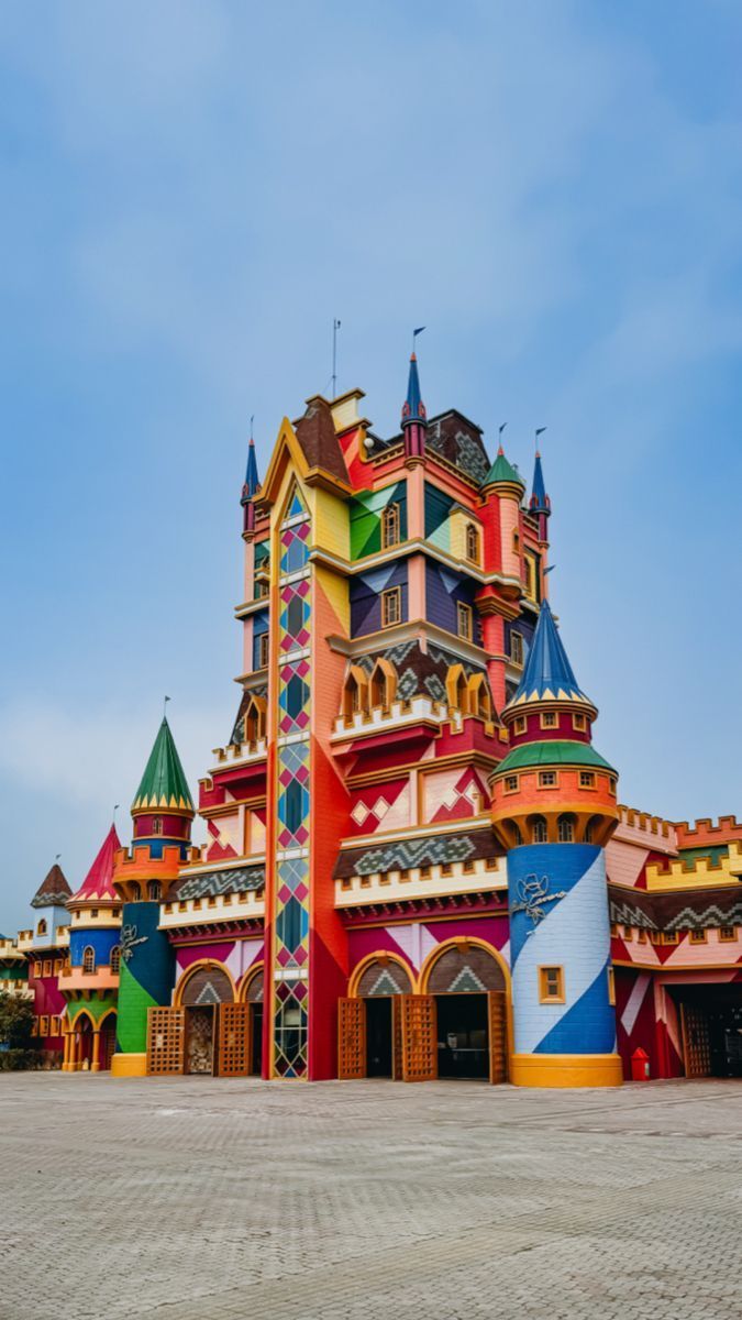 Fachada colorida do castelo contra um céu azul; arquitetura intrincada com tons vibrantes.