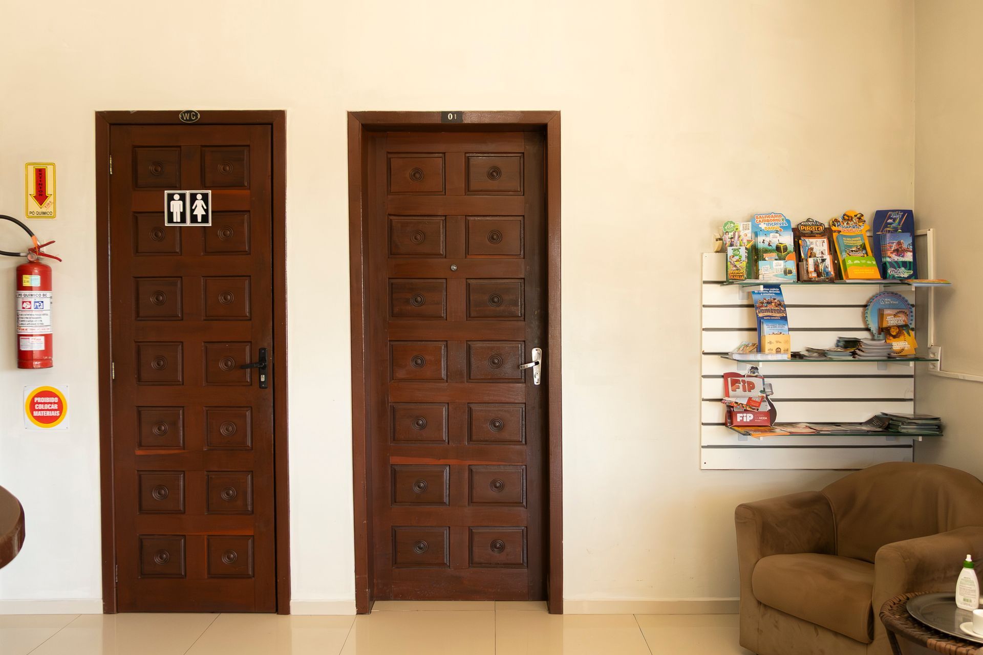 Duas portas marrons, uma placa de banheiro