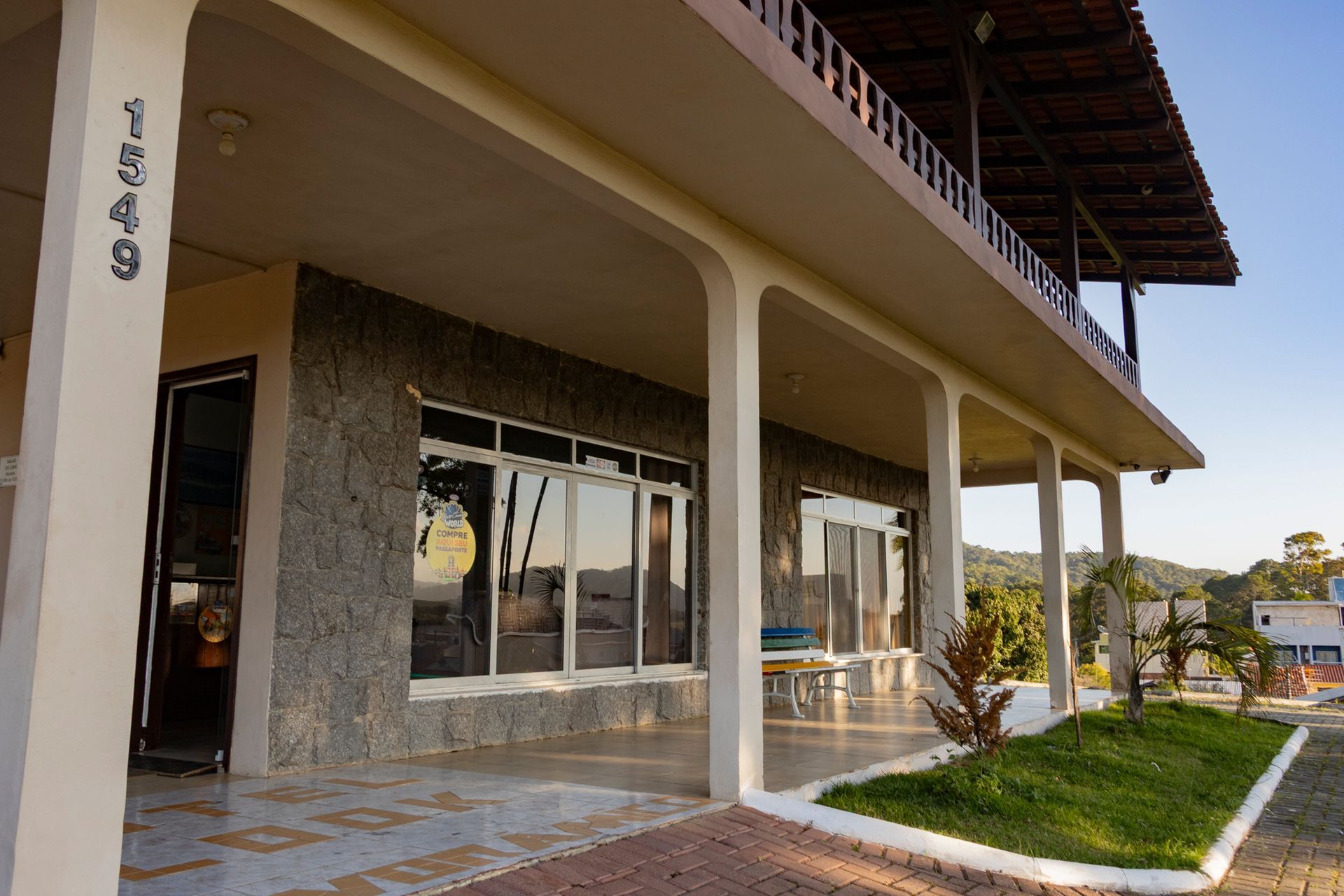 Fachada do edifício com muro de pedra, varanda e sacada no segundo andar. Número 1949 visível.