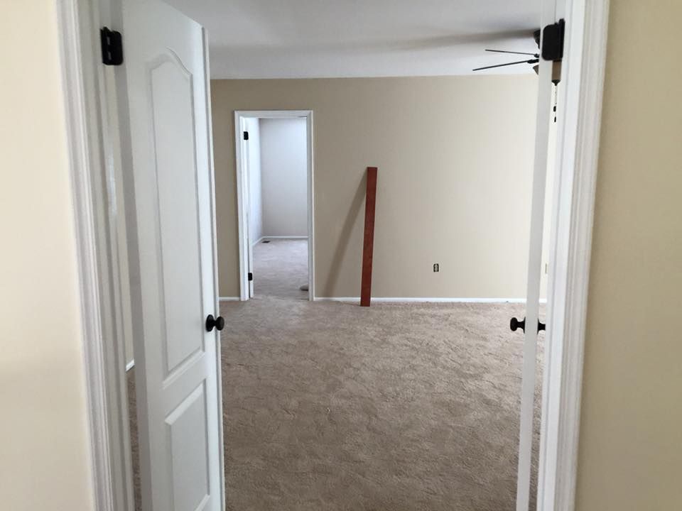 Open doorway leading to a carpeted room with a doorway to another room; tan walls.