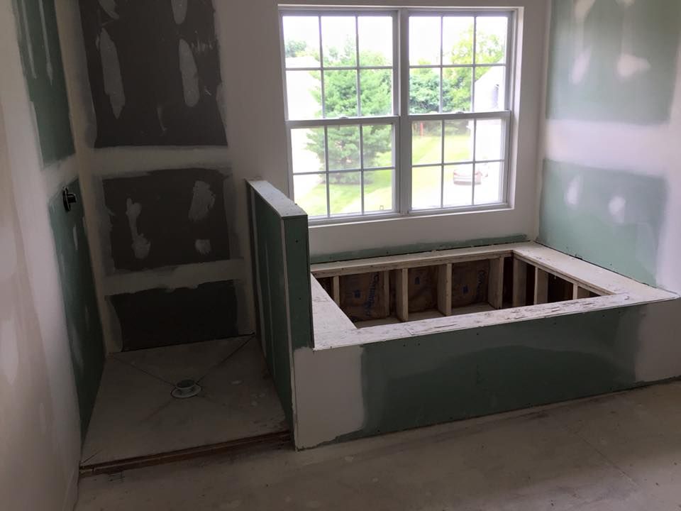 Bathroom under construction with a built-in tub area, window, and wall niche. Drywall is installed.