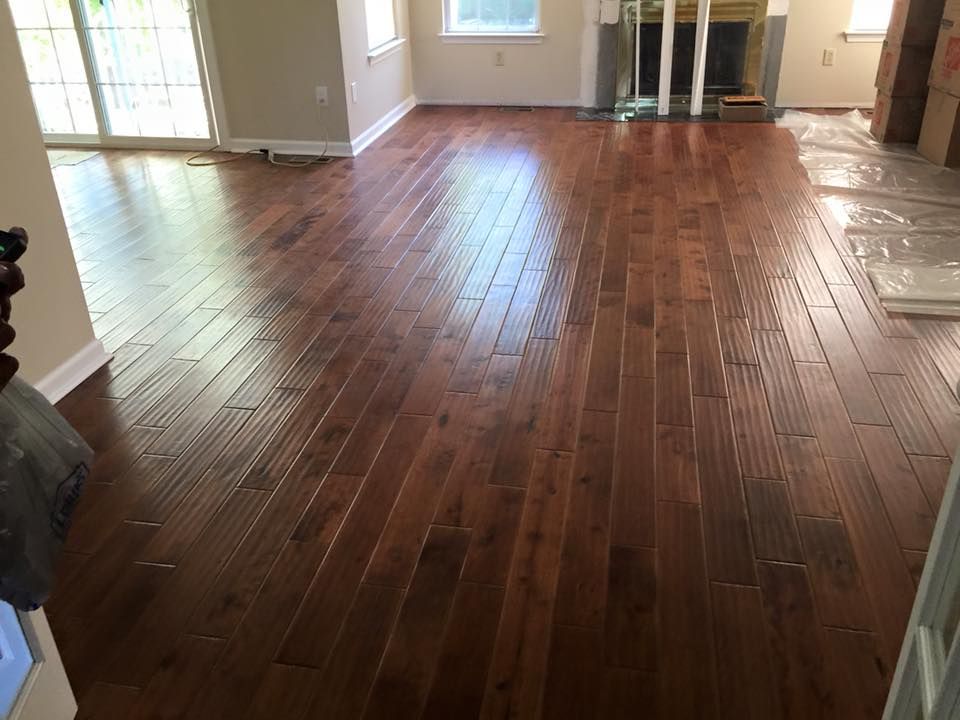 Newly installed, shiny, dark wood flooring in a living room, reflecting light.