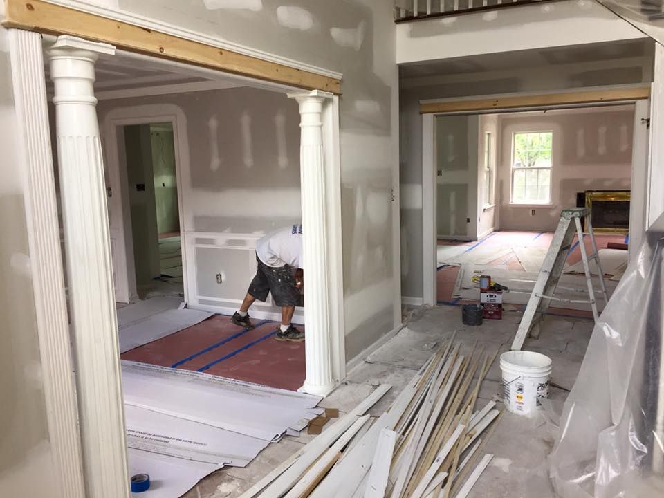 Construction site interior with worker, columns, drywall, and trim.