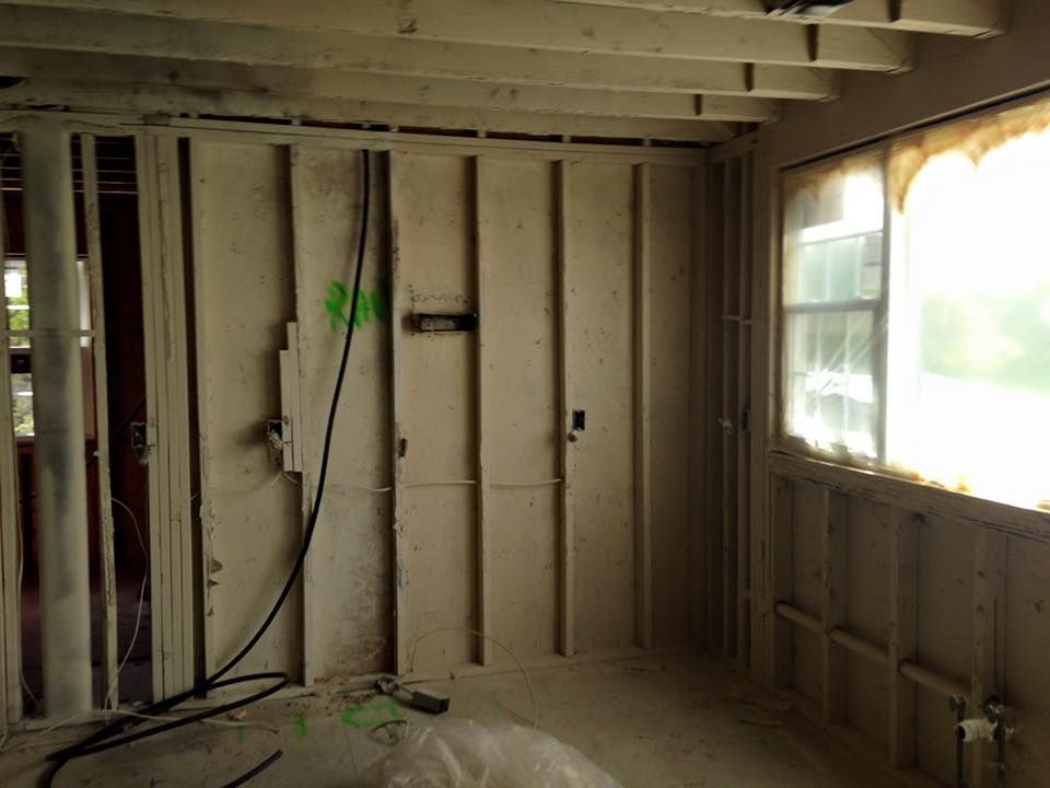 Interior view of a room under construction with exposed wooden framing and a window.