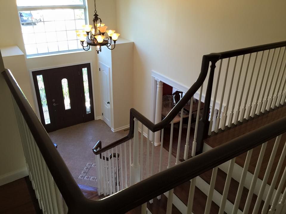 View from the top of a staircase, looking down at the front door. Brown railings and white spindles.