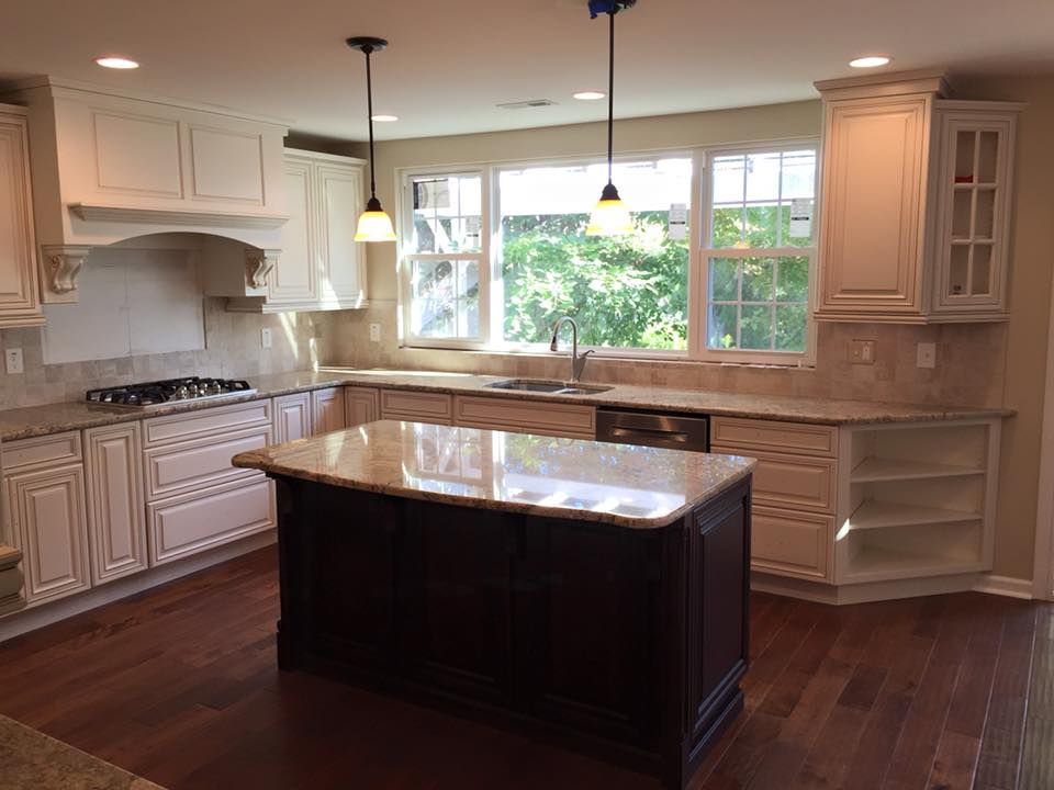 Kitchen with cream cabinets, dark island, granite countertops, and hardwood floors.