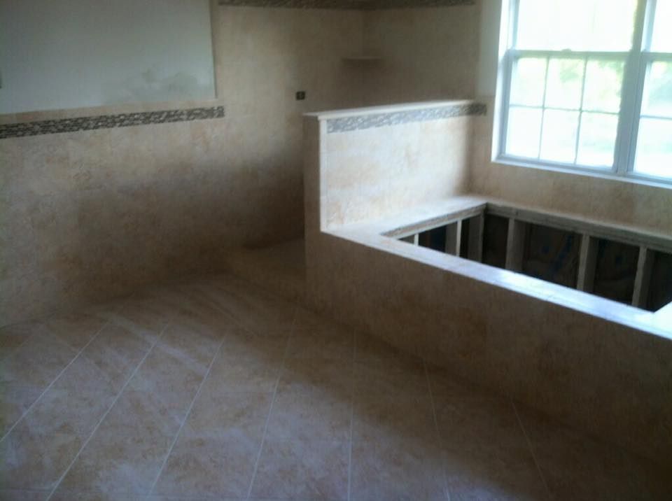 Bathroom under construction with tan tile and a built-in tub.