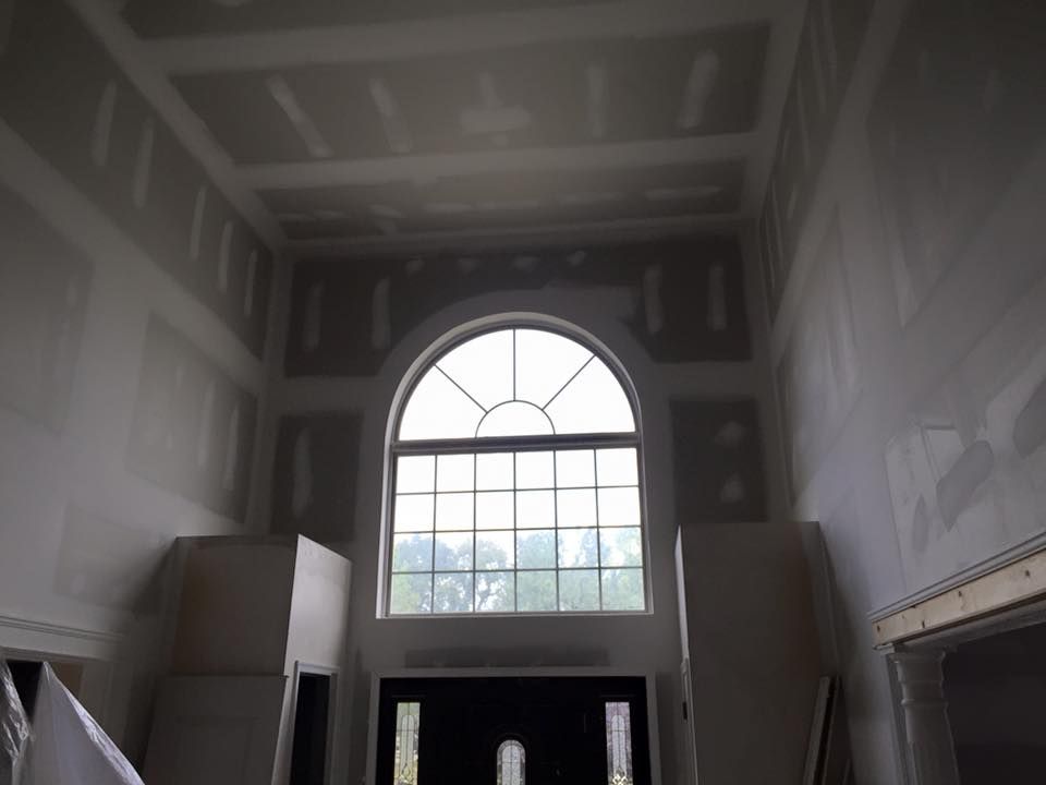 Interior construction with drywall around an arched window and entrance, unfinished.