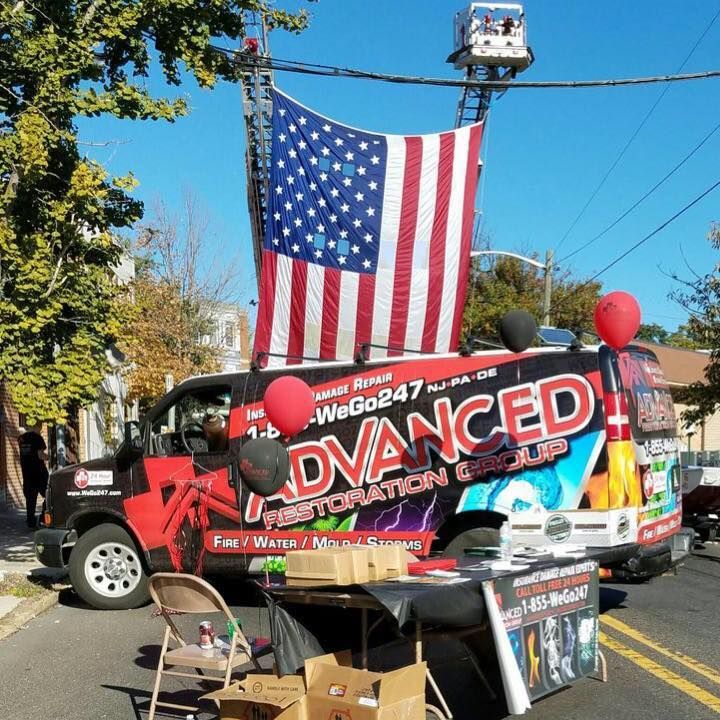 Van with American flag, balloons, and display table for Advanced Restoration Group.