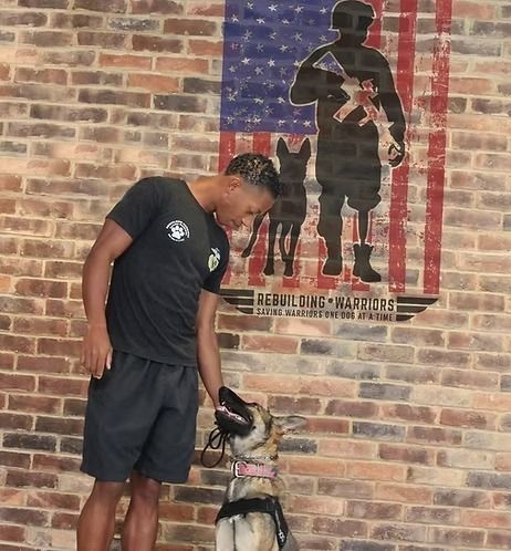 A man standing next to a dog in front of an american flag
