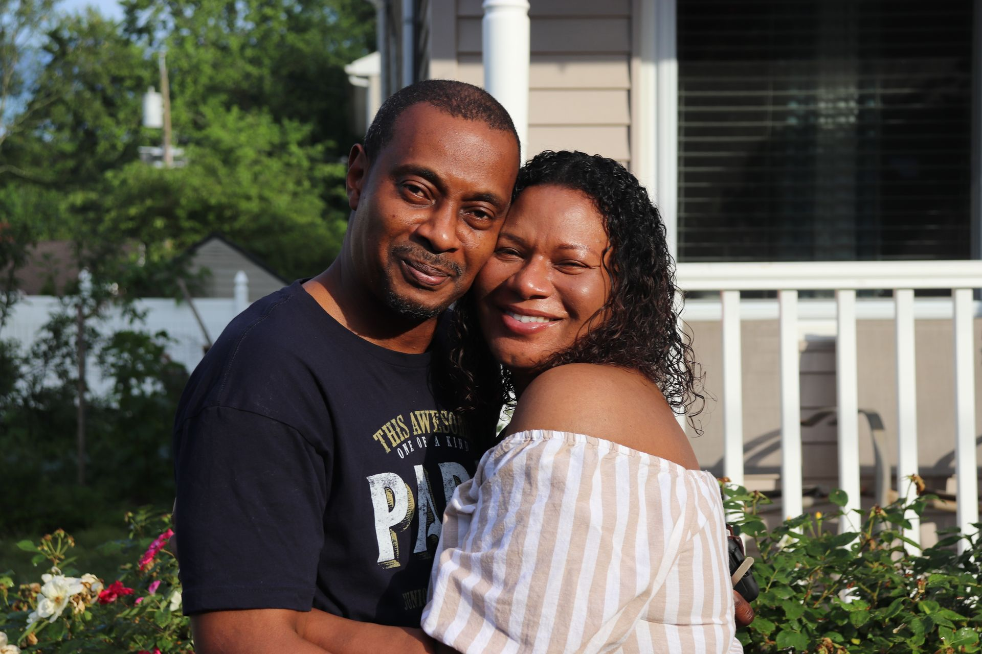 A man and a woman are hugging each other and smiling for the camera.
