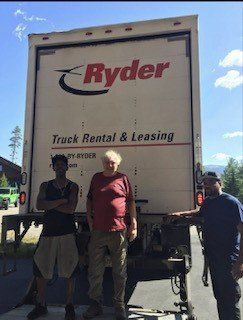 Three men are standing in front of a ryder truck