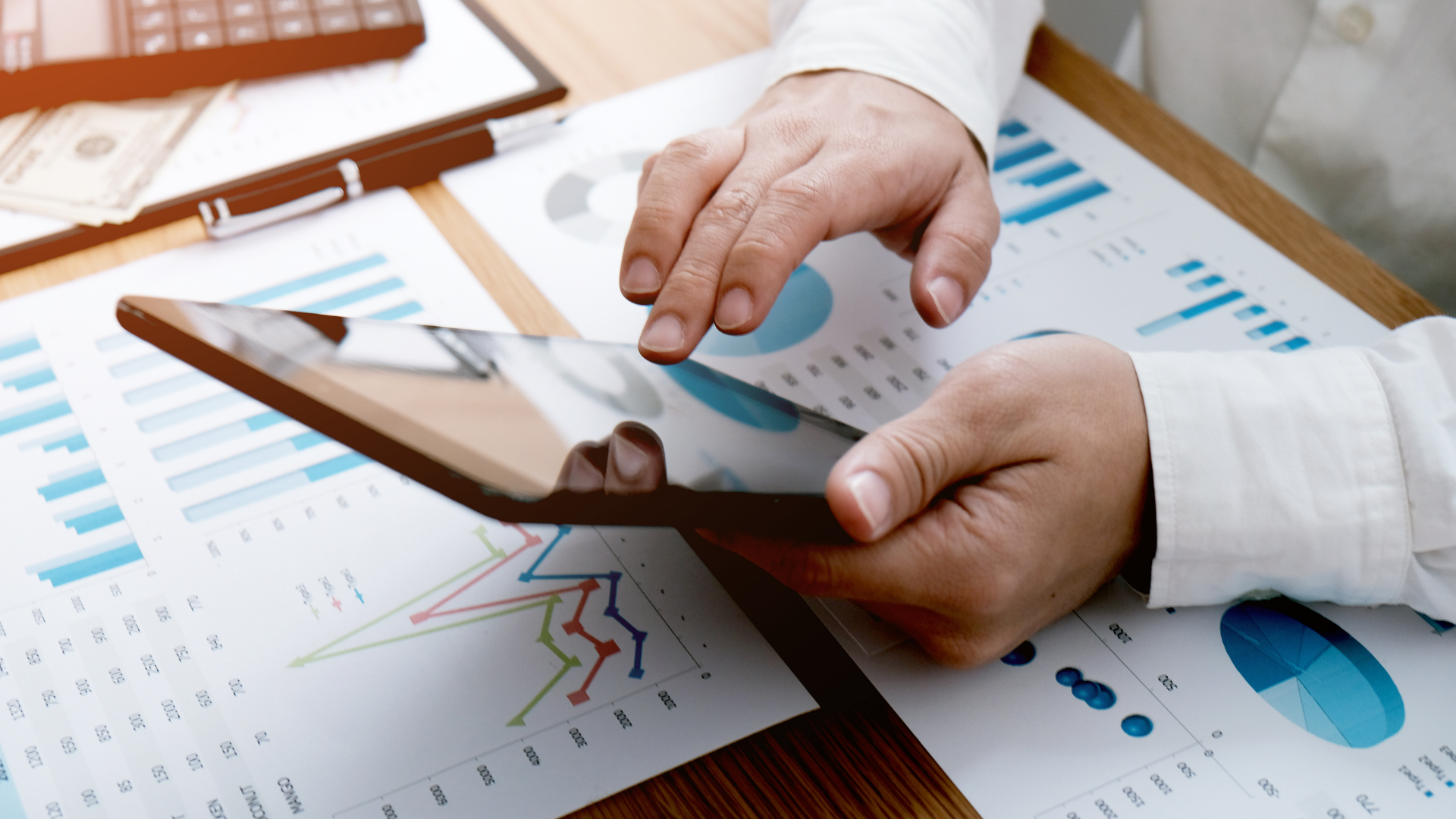 A person is using a tablet and a calculator on a table.