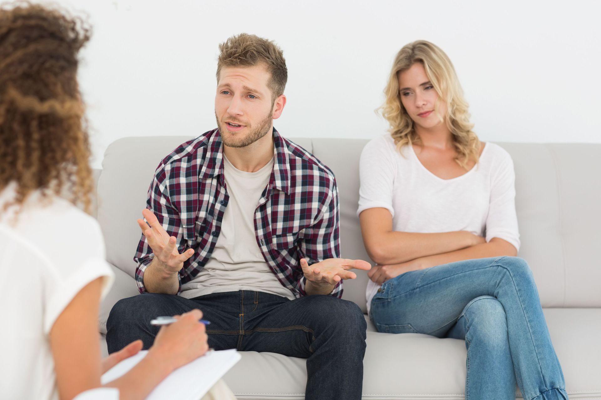 Man & woman sitting in couples therapy talking about their relationship issues. Overcoming infidelity can happen through marriage counseling via online therapy in Colorado.