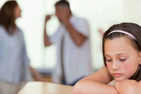 Depressed little girl with fighting parents in the background indicating divorce-related therapy services