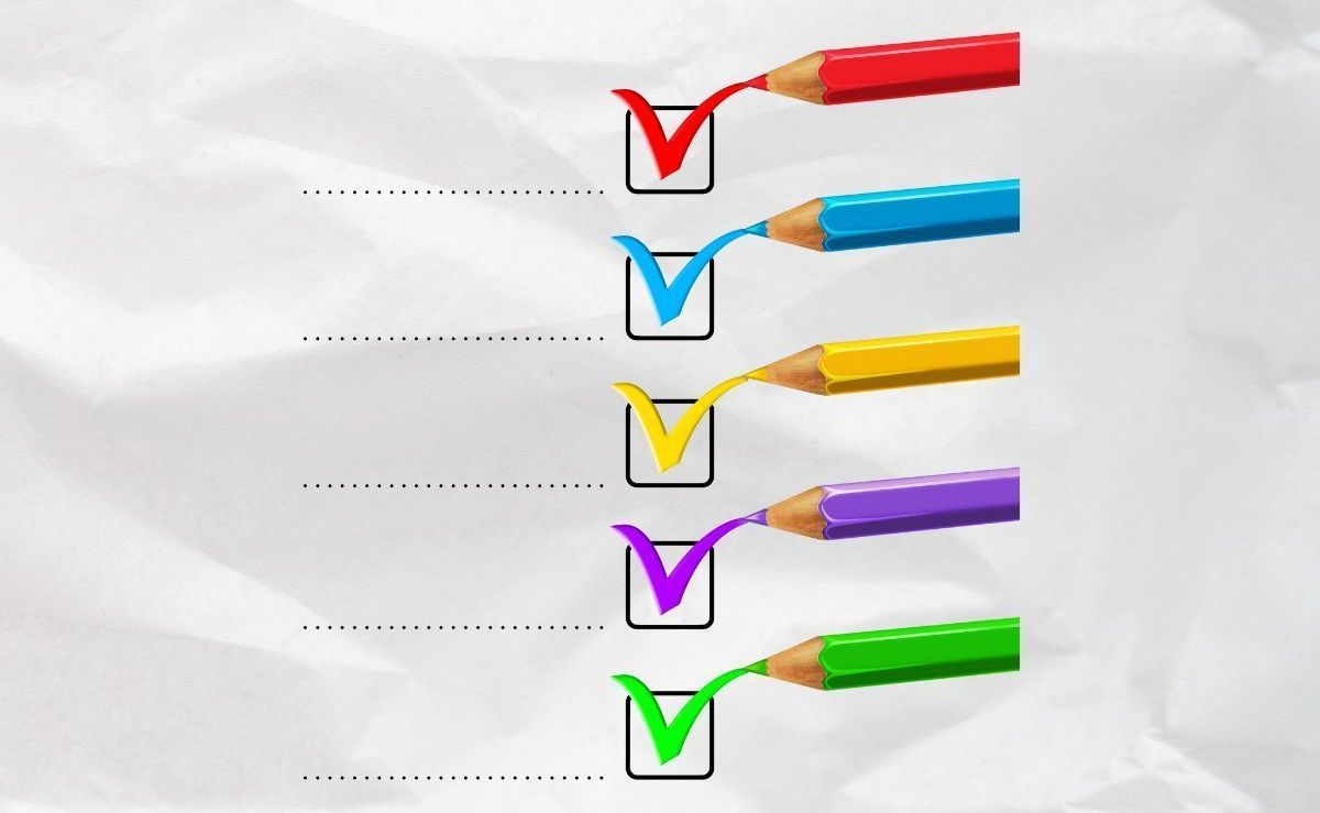 Five colored pencils, each drawing a matching checkmark in a square box against a white, crumpled background.
