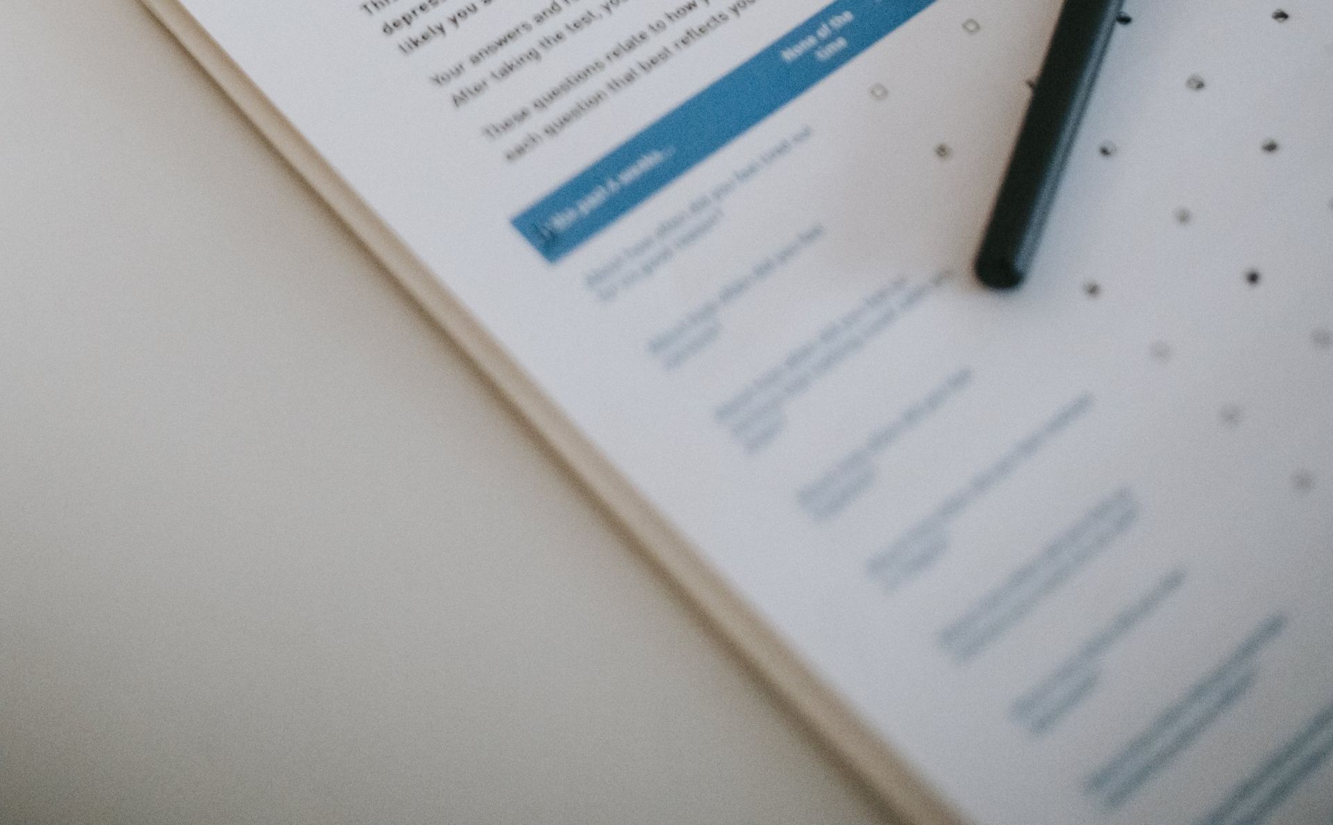 A close-up of a questionnaire on a white surface with a black pen resting on it.