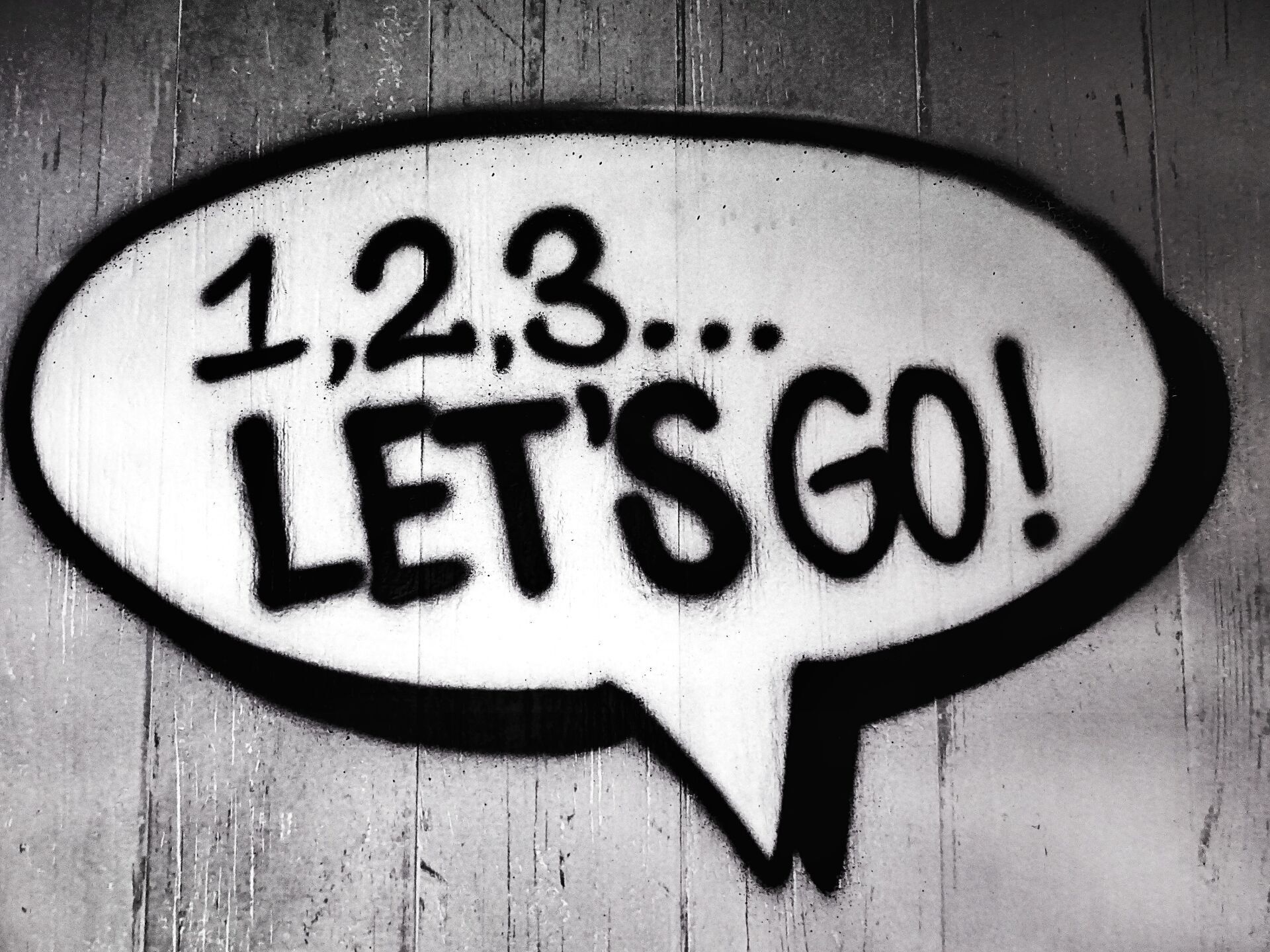 A black and white speech bubble graphic on a textured wall containing the text 