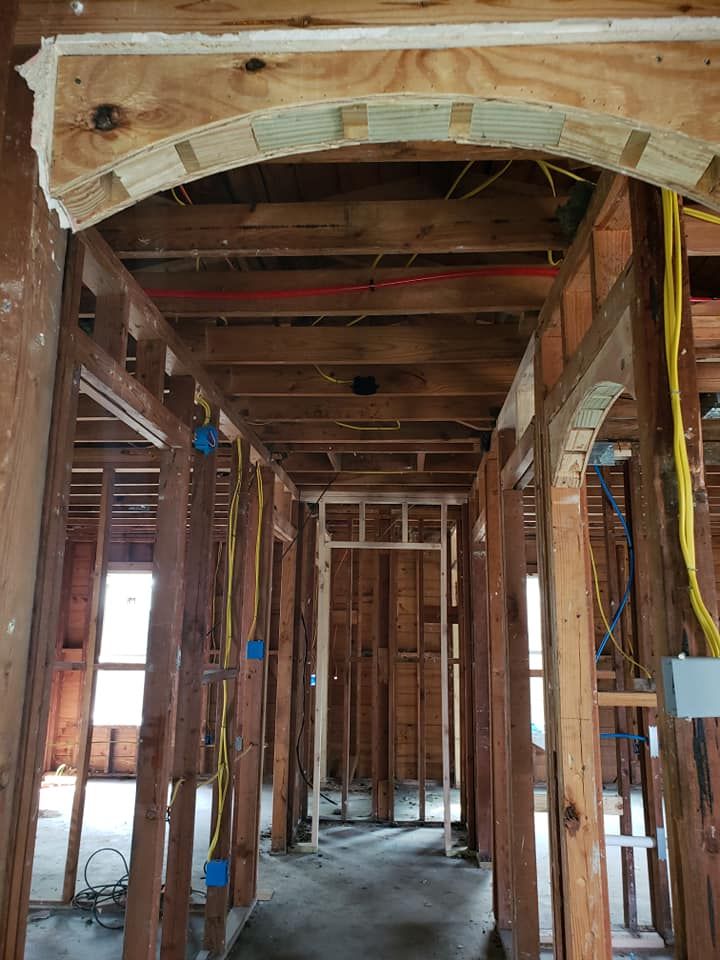 Interior view of a residential construction site featuring arched wooden doorways and exposed wall framing.