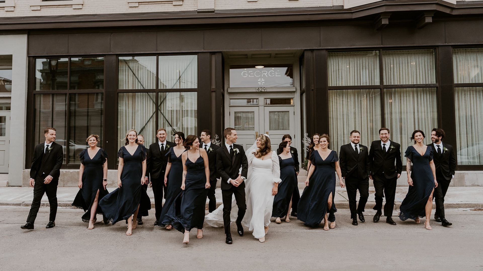 a bride and groom are standing on a dock next to a body of water .