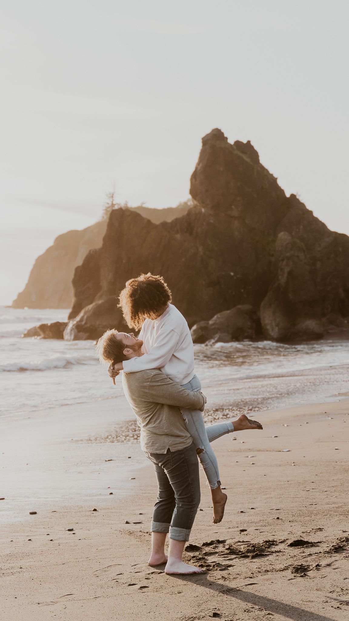 A man is holding a woman in his arms on the beach.